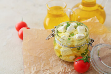 Jar with tasty feta cheese, oil and tomatoes on light background
