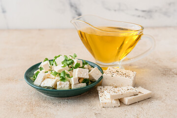 Plate with tasty feta cheese, oil and parsley on light background