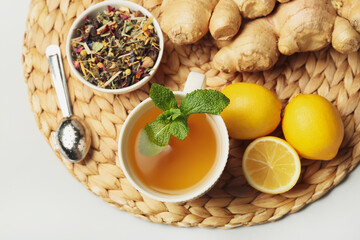 Cup of tea with ginger, mint and lemons on light background, closeup