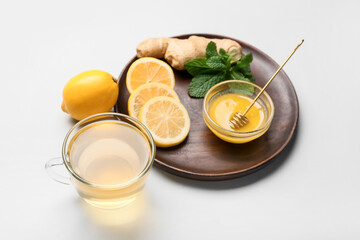 Cup of tea with ginger, honey and lemon on light background