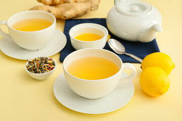 Teapot and cups of tea with ginger on color background