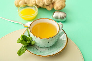 Cup of tea with ginger, mint and honey on color background