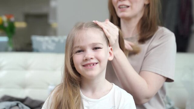 Mom combs her daughter and makes two tails, hurry, it turns out not immediately. preparing the child for the performance on stage. eye makeup.
