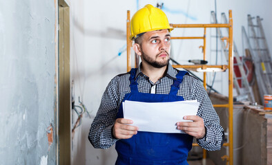 Serious builder is looking on the project of work for the object.
