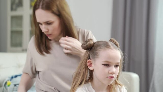 Mom makes a hairstyle her daughter, hurry, it turns out not immediately. preparing the child for the performance on stage. eye makeup.