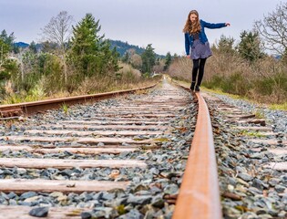 Girl balancing on old train track rail