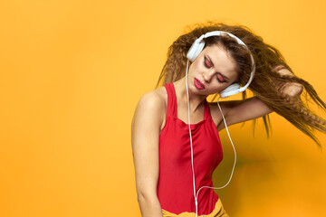woman in headphones listening to music red t shirt emotions fashion yellow background lifestyle