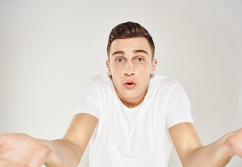 Surprised man spreads his hands to the sides on a light background cropped view