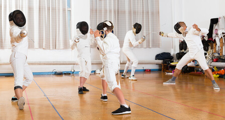 Obraz premium Portrait of young fencers with instructor engaged in fencing in gym
