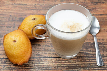 tasse de café au lait et madeleine sur une table