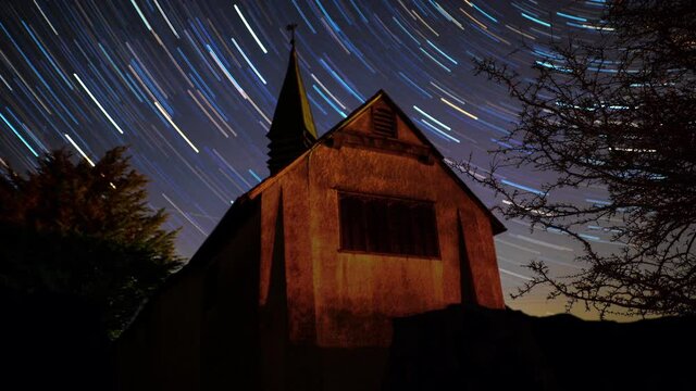 Star trails time lapse of dark night sky over light painted chapel in Mendip Hills, Somerset UK
