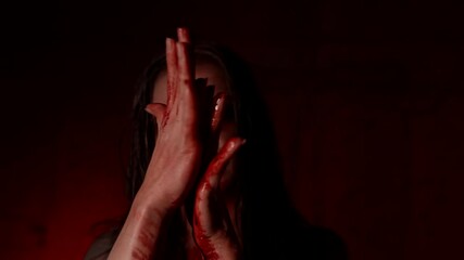 vampire woman with black eyes is licking blood from her arms, possessed by devil lady