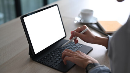 Close up view of woman hand holding stylus pen and working on computer tablet at office desk.