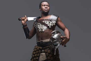 Fototapeta na wymiar Violent gladiator with sword against gray background