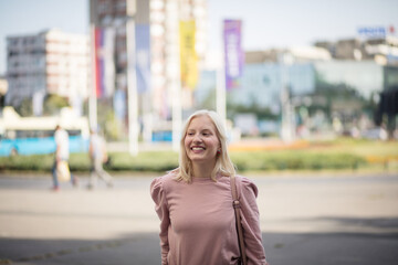Fototapeta premium Portrait of smiling blond woman on the street.