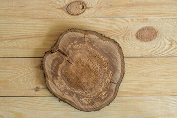 On a wooden background lies a round section of cherry wood with cracks and a rotten middle
