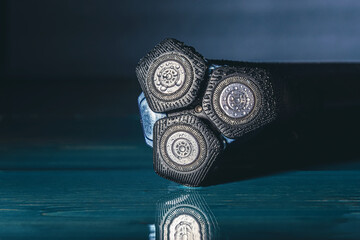 Rotary electric face shaver for wet and dry shaving on a dark blue background. Selective focus.