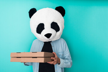 Man in panda mask holding two pizza boxes isolated over blue background