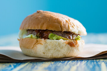 Burger with beef cutlet, sauce and salad copy space side view. Food delivery concept, restaurants operating in quarantine covid 19.