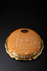 Cake with the inscription cheesecake. Classic cheesecake on black, dessert. Round cake, black background. Cream pie with the inscription.