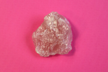 Piece of polished pink quartz on purple background. Minimal color still life Narrow focus line, shallow depth of field