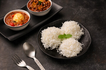 Noolappam/Idiyappam/rice noodles, a popular traditional steam cooked Kerala breakfast dish with hot and spicy egg roast curry on a houseboat, Alleppey, India. South Indian food. noolputtu Sri lankan