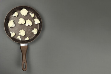 Raw cauliflower in frying pan on grey background. Copy space for text