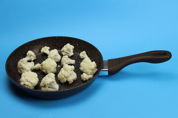 Raw cauliflower in frying pan on blue background, healthy food concept, diets