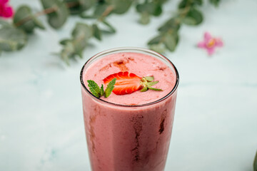 Glass of strawberry smoothie cocktail on the blue background