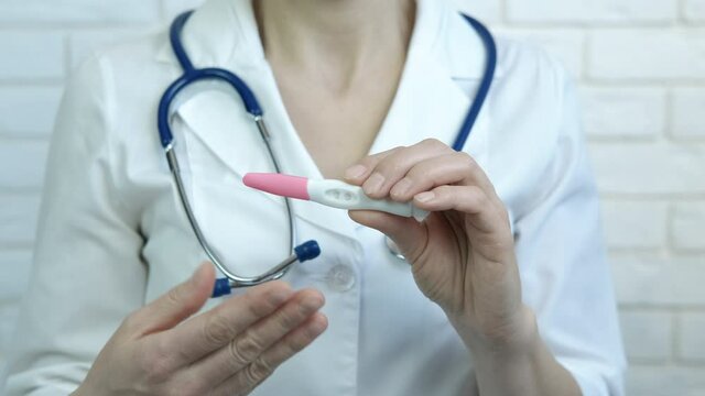 Doctor with pregnancy test. A doctor hold in her hands a pregnancy test and speak about woman treatment online.