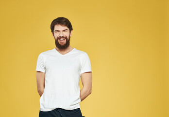 Fototapeta na wymiar Portrait of a man on a yellow background in a white T-shirt and dark trousers
