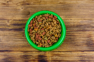 Bowl with pet food on a wooden background. Top view