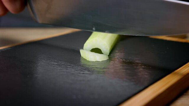 Female hands slicing celery stalk with knife. Macro shot, 150 fps, slow motion