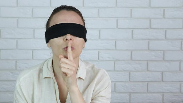 Showing silence gesture. A blindfolded female show to keep silence in the room.