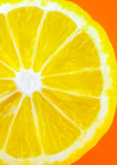 Close up photo of lemon texture on the orange background. Fruit cut in half, inside, macro view.