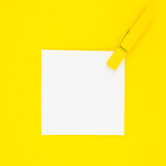 Blank white To Do List Sticker with yellow wooden clothespin. Close up of reminder note paper on the yellow background. Copy space. Minimalism, original and creative photo.