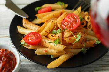 Plate with pasta with tomato sauce and cutlery, close up
