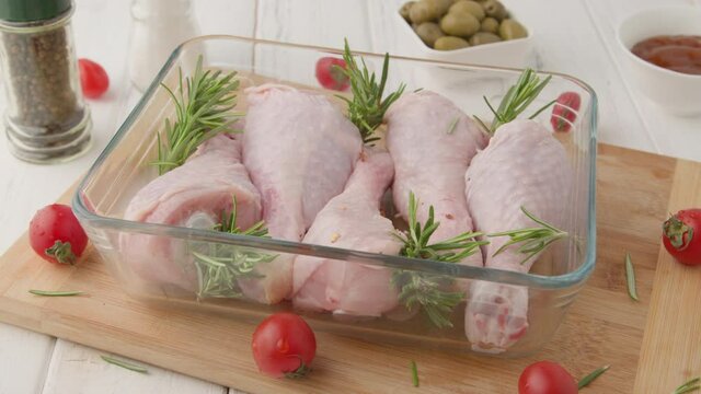 Chef marinates raw chicken legs with sauce.Salt on raw chicken legs.
Cooking chicken legs with spices, garlic and rosemary. Cooking food concept.