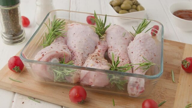Chef marinates raw chicken legs with sauce.Salt on raw chicken legs.
Cooking chicken legs with spices, garlic and rosemary. Cooking food concept.