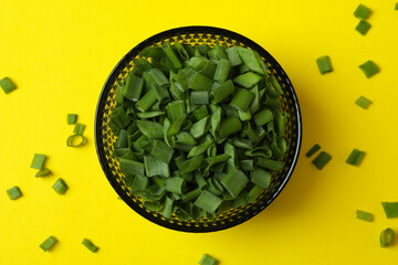 Bowl of chopped green onion on yellow background