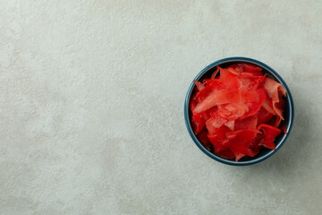 Bowl with red pickled ginger on white textured background, top view