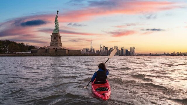 Cinemagraph Seamless Continuous Loop Animation. Adventurous Woman Sea Kayaking near the Statue of Liberty. Colorful Sunrise sky Art Render. Taken in Jersey City, New Jersey, United States.