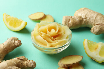 Bowl with pickled ginger, lemon and ginger on mint background