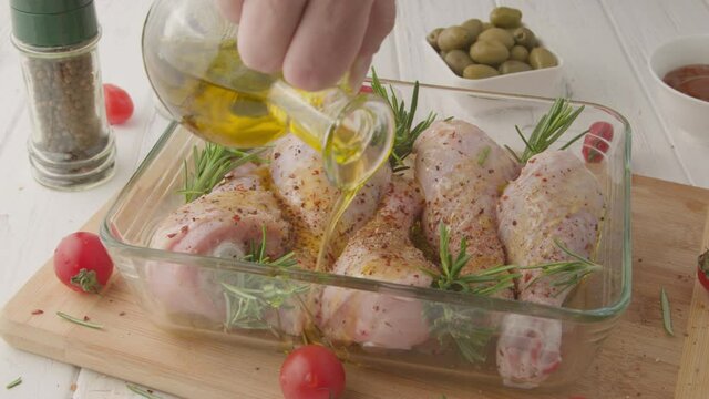 Chef marinates raw chicken legs with sauce.Salt on raw chicken legs.
Cooking chicken legs with spices, garlic and rosemary. Cooking food concept.