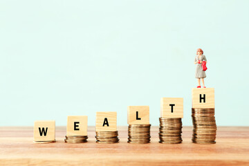 wealth text written on wooden cubes with stacked coins . growth and success concept