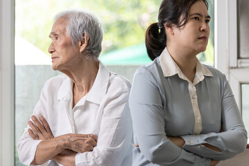 Displeased asian daughter sitting back to back after quarrel,argue feel offended at home,angry upset elderly mother with crossed arms,relationship difficulties,conflict,family crisis,lifestyle problem - obrazy, fototapety, plakaty