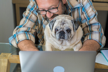 Portrait of man and dog working together at home with laptop computer - concept of free smart work lifestyle people - caucasian typing on keyboard at workstation - modern online job digital life