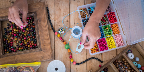 Top view of woman doing jewelry beads accessories with colorful cords - home work job concept...