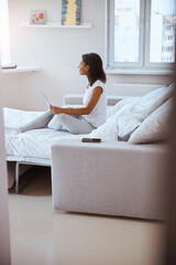 Beautiful young woman using notebook in bedroom