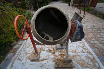 An old concrete mixer in the backyard of a rural house 